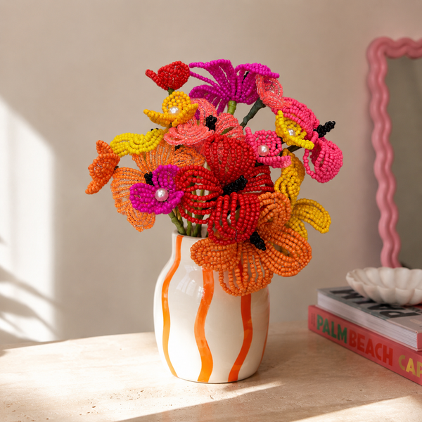 Fleurette, bouquet tropical en perles de rocaille orange, jaune et fuchsia à cœurs nacrés, dans un vase blanc rayé orange, fait main à Châteauroux, Perle Moi Ça