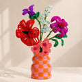 Fleurette, bouquet vitaminé en perles de rocaille rouge, fuchsia et corail, dans un vase à damier orange et rose, fait main à Châteauroux, Perle Moi Ça