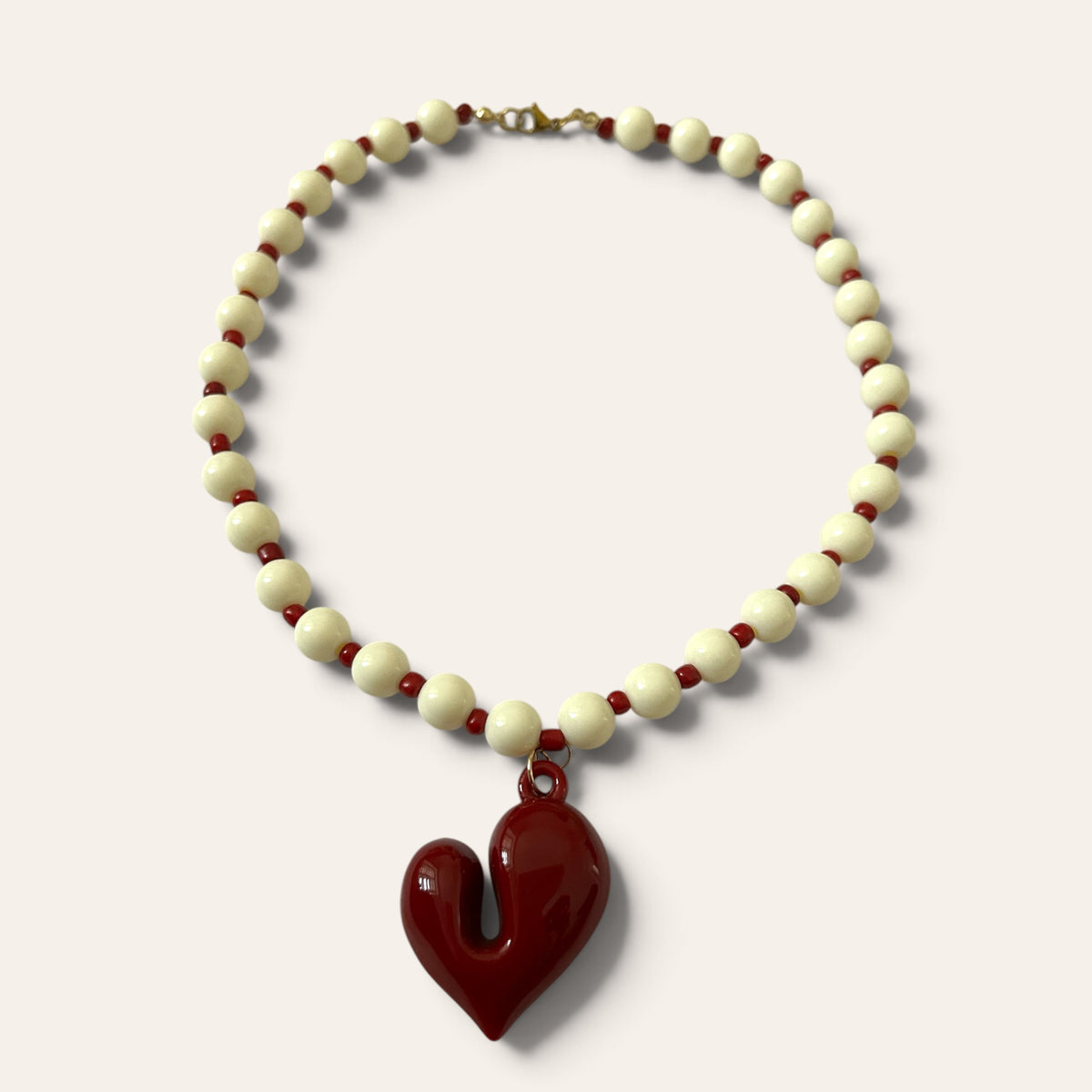 Josette, collier tissé de perles crème et bordeaux sur fil nylon, cœur en acrylique, à plat, Perle Moi Ça