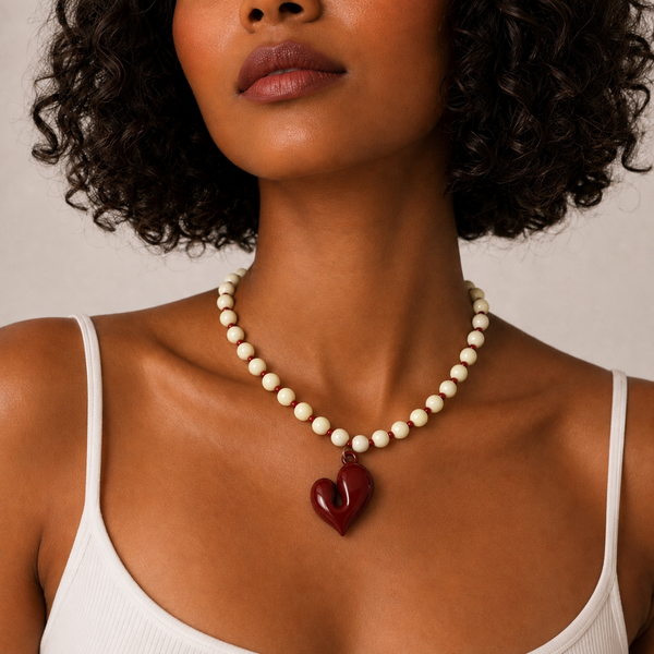 Josette, collier de perles crème et rocailles bordeaux avec grand cœur bordeaux, porté sur débardeur blanc, Perle Moi Ça