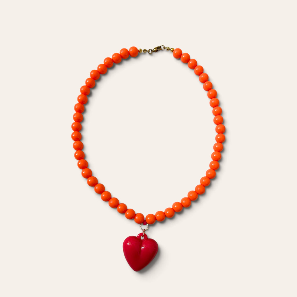 Josette, collier tissé de perles orange en acrylique et cœur fuchsia, à plat, Perle Moi Ça