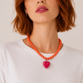 Josette, collier de perles orange avec grand cœur fuchsia, porté sur tee-shirt blanc, Perle Moi Ça