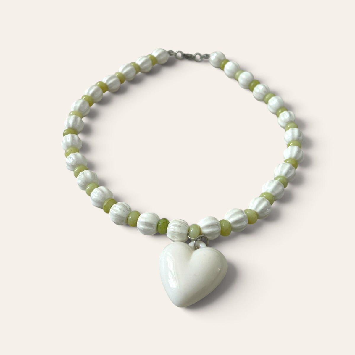 Détail du collier Josette Lux : grand cœur blanc en acrylique, perles blanches et vertes, fermoir argenté, Perle Moi Ça