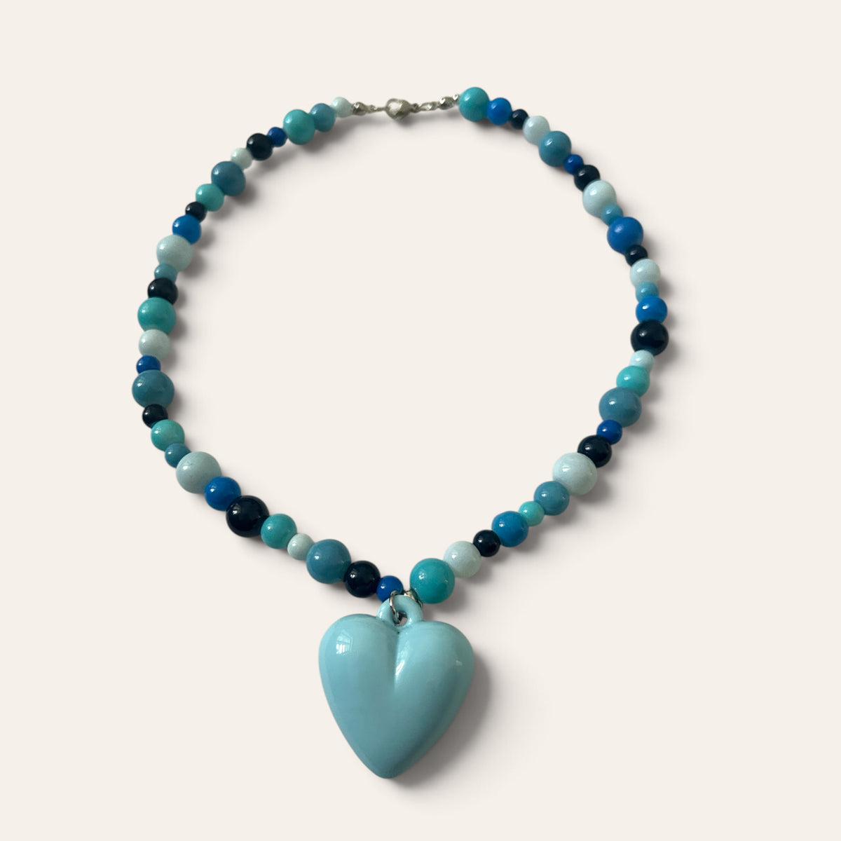 Josette Lux, collier tissé de perles de verre turquoise, marine et bleu ciel, cœur en acrylique, à plat, Perle Moi Ça