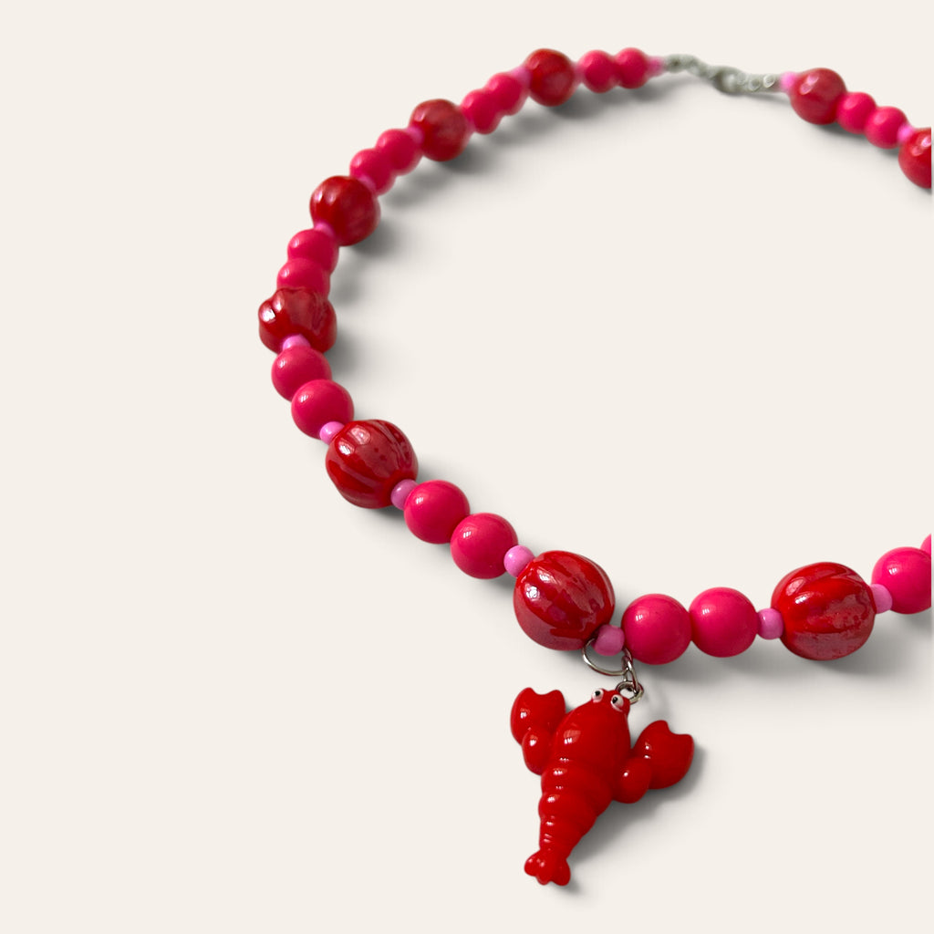 Détail du collier Josette Lux : homard rouge en acrylique, perles rouges côtelées en céramique et perles roses, Perle Moi Ça