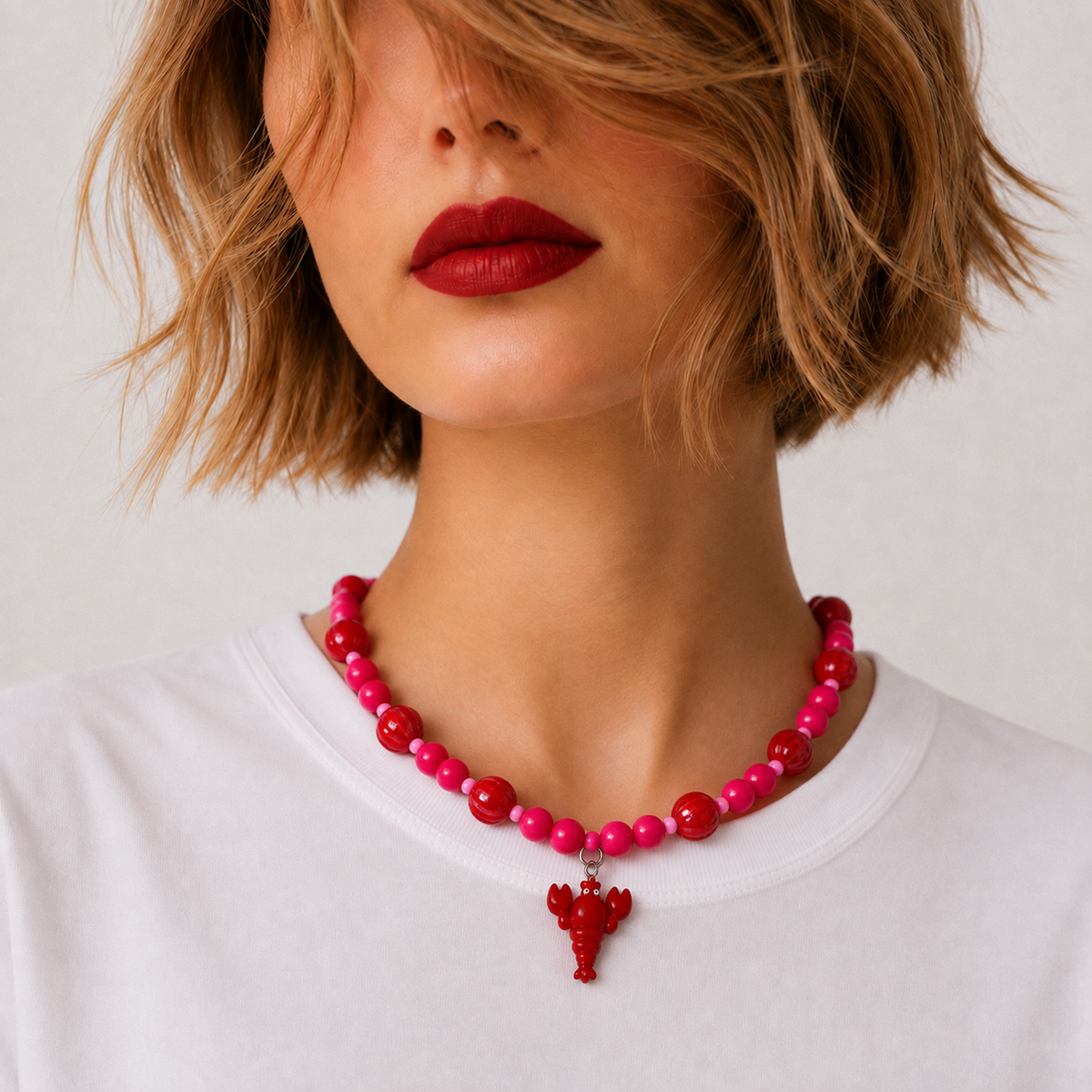 Josette Lux, collier de perles rouges et roses avec petit homard rouge, porté sur tee-shirt blanc, Perle Moi Ça