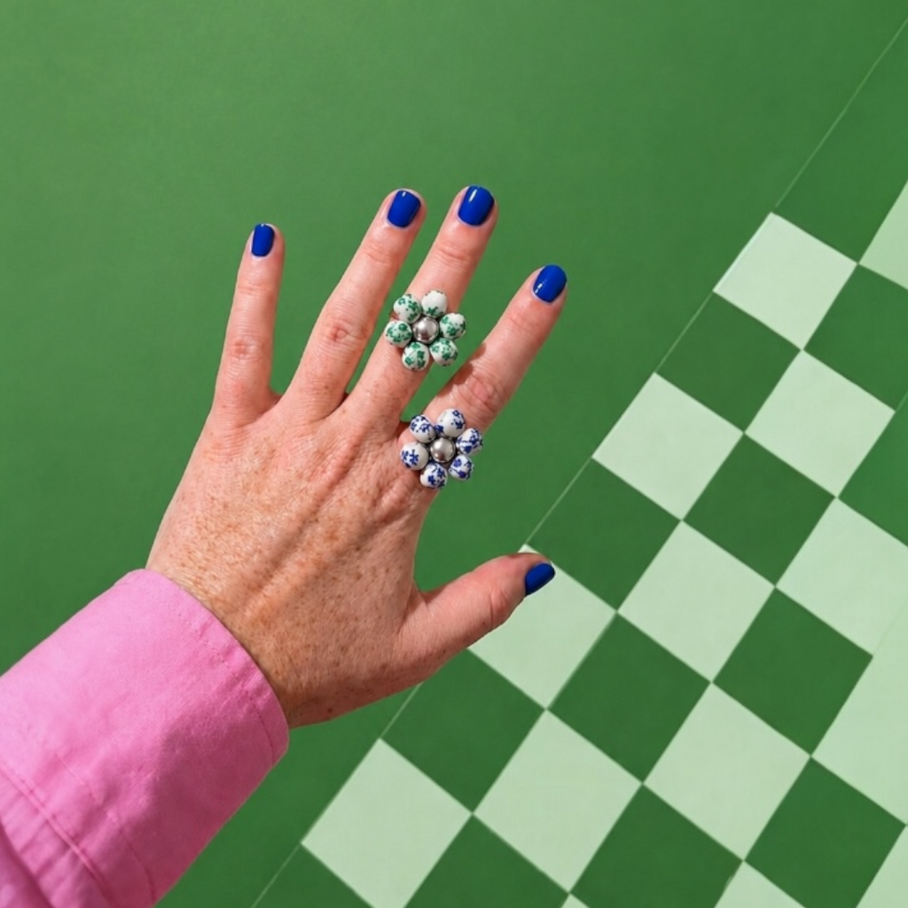 Odette, bagues fleur en perles de céramique vertes et bleues portées sur la main, anneau ajustable doré et argenté, faites main à Châteauroux, Perle Moi Ça
🎯