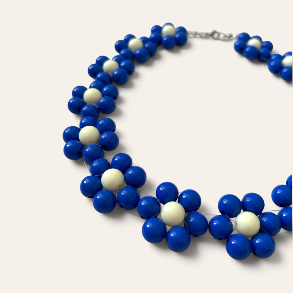 Gros plan collier Odette, fleurs en perles acryliques bleues et crème, détail du motif floral, fait main à Châteauroux, Perle Moi Ça