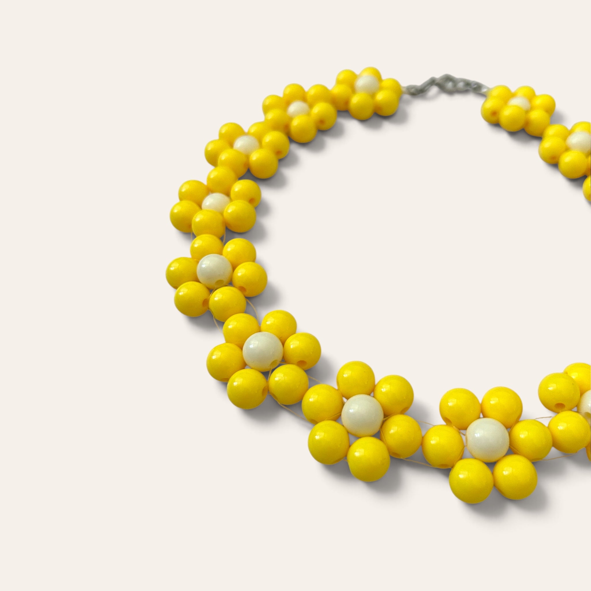 Gros plan collier Odette, fleurs en perles acryliques jaunes et crème, détail du motif floral, fait main à Châteauroux, Perle Moi Ça