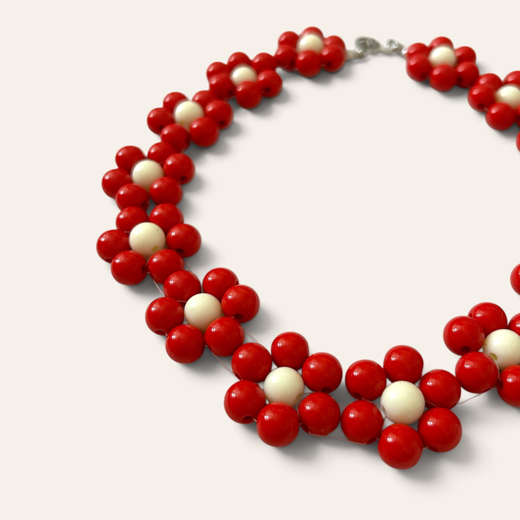 Gros plan collier Odette, fleurs en perles acryliques rouges et blanches, détail du motif floral, fait main à Châteauroux, Perle Moi Ça