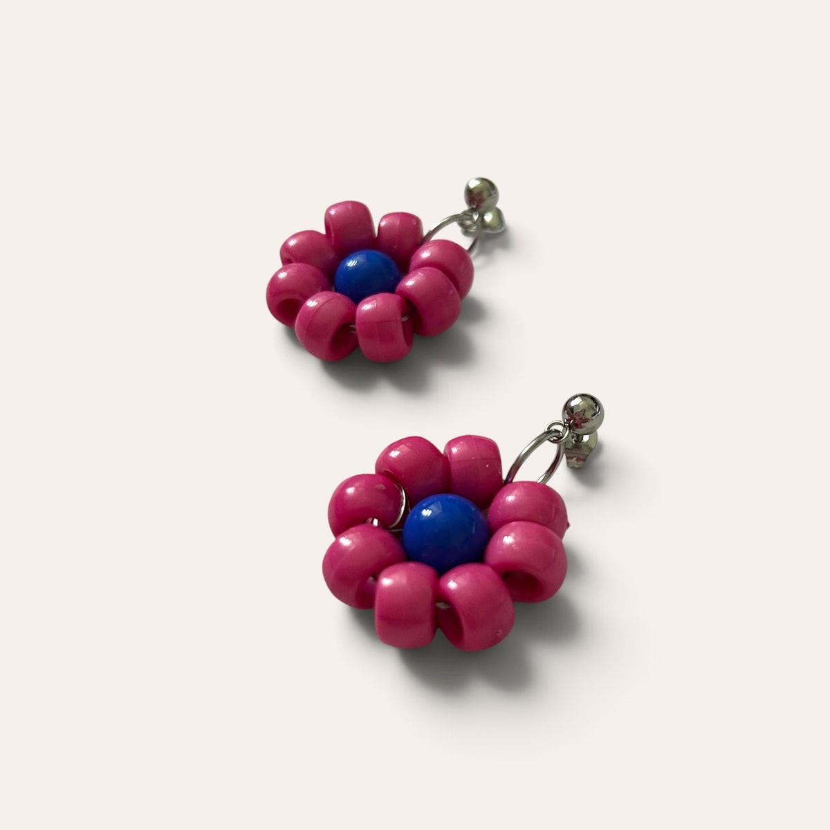 Paire de boucles Paulette : fleur fuchsia à cœur bleu en perles d'acrylique, vue à plat, Perle Moi Ça