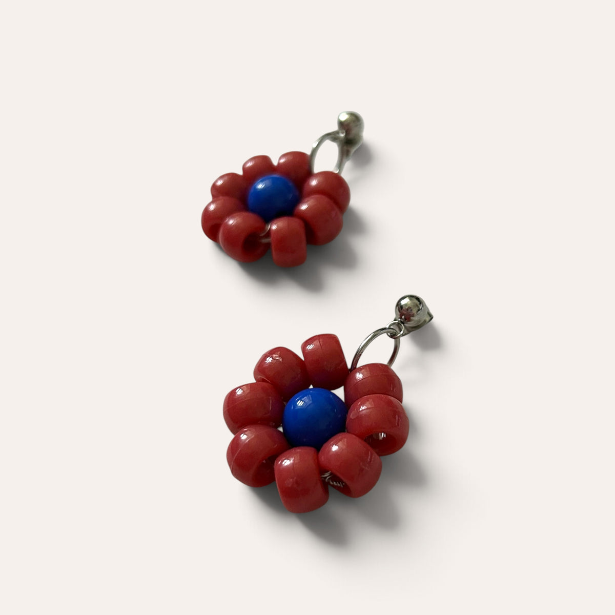 Paire de boucles Paulette : fleur rouge à cœur bleu en perles d'acrylique, vue à plat, Perle Moi Ça