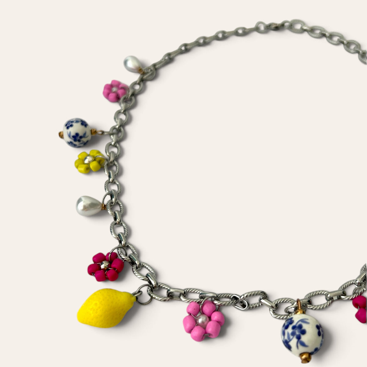 Détail du collier Pierette : citron jaune, fleurs tissées rose et fuchsia, goutte nacrée et perle de céramique, Perle Moi Ça