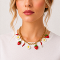 Pierette, collier de breloques fraises, marguerites et piments sur chaîne dorée, porté avec un tee-shirt blanc, Perle Moi Ça